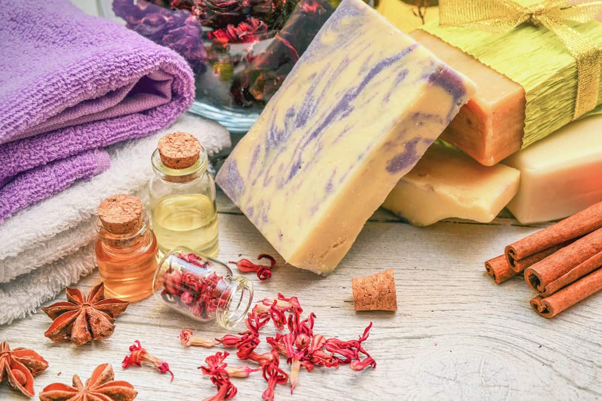 A handmade soap with essential oils on the side and towels in the background