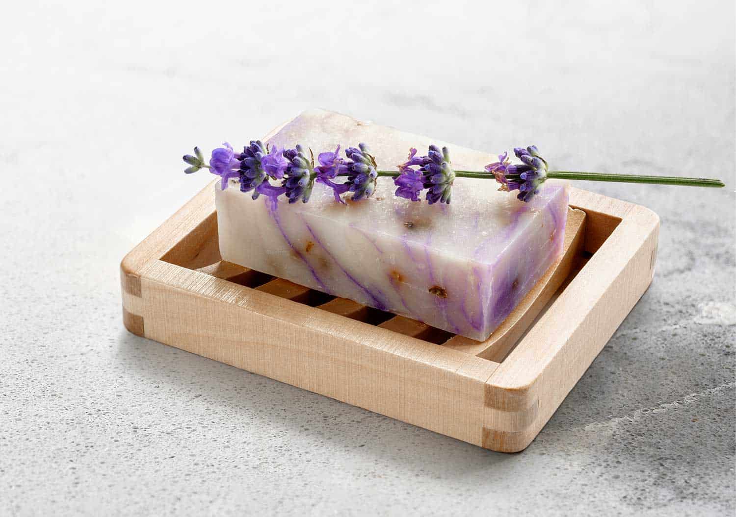 Homemade lavender soap on wooden soap dish on marble table