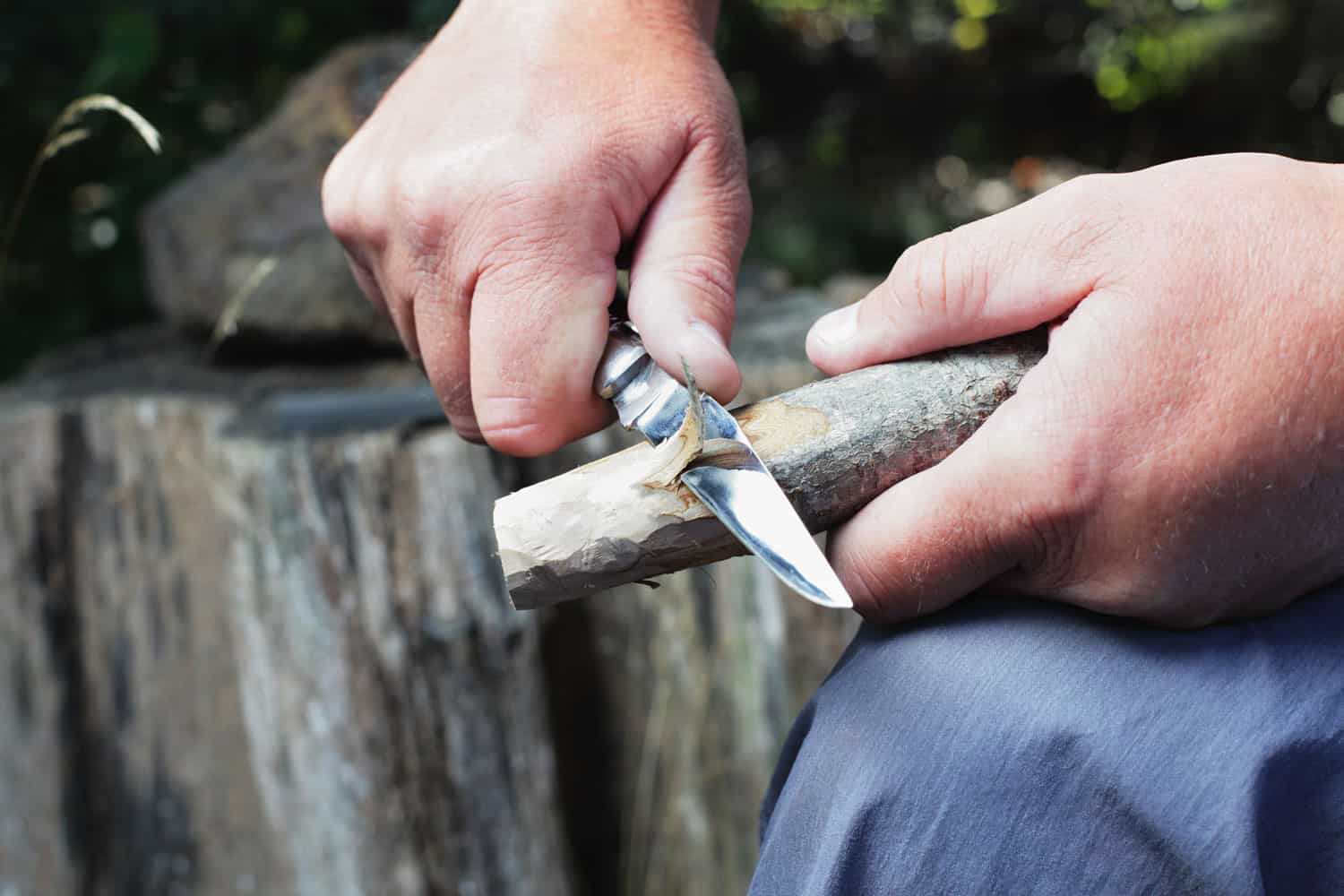 A man sharpening a stick using his knife