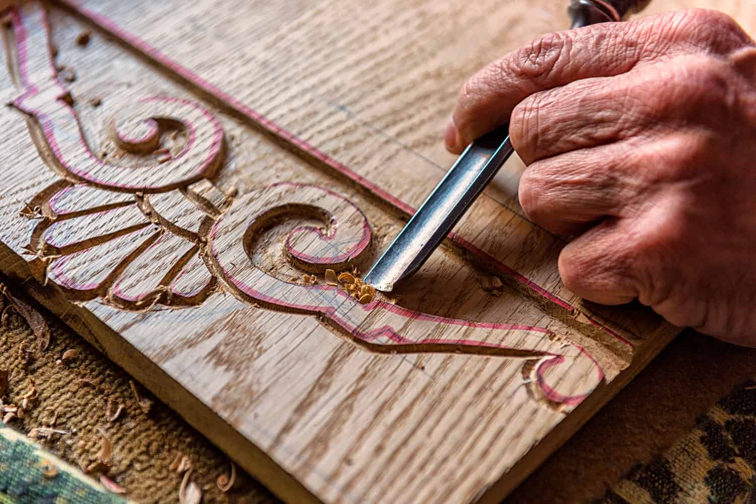 A elderly man doing wood carving work using a chisel