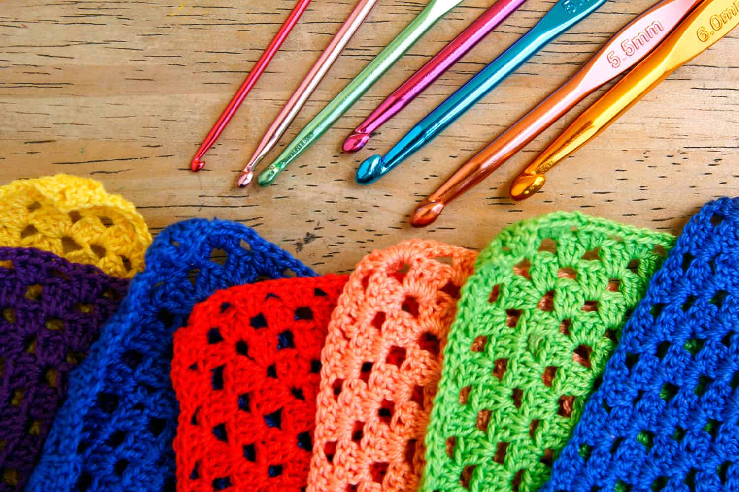 A complete set of crochet needles and small crocheted granny squares