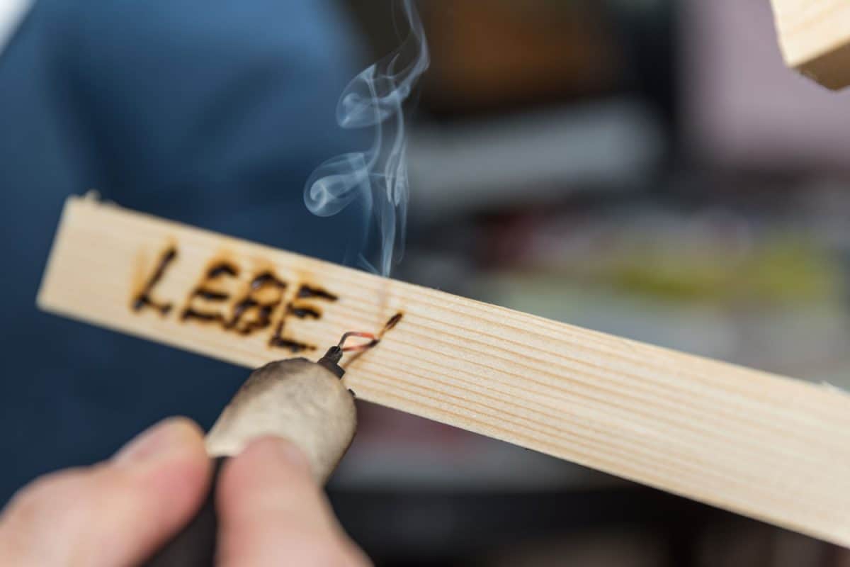 A man doing pyrography work on a small piece of wood, How Do You Burn Names Into Wood?