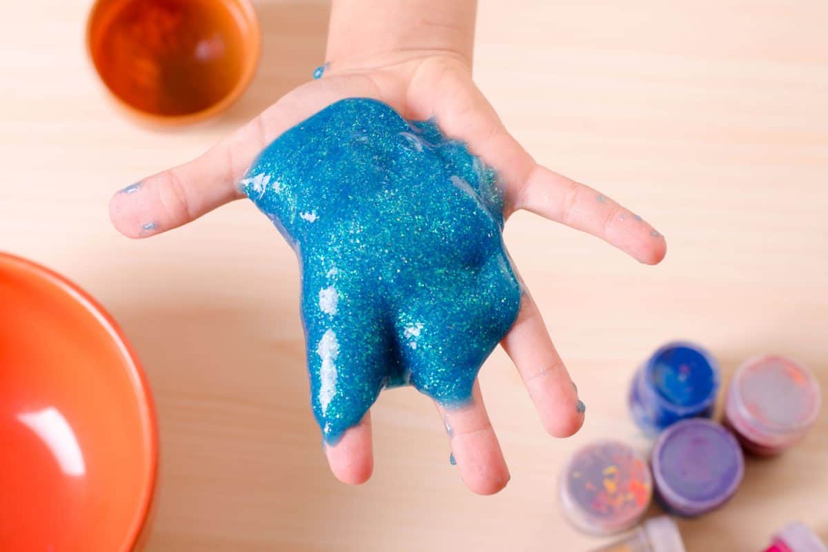 A child holding a blue colored glitter glue