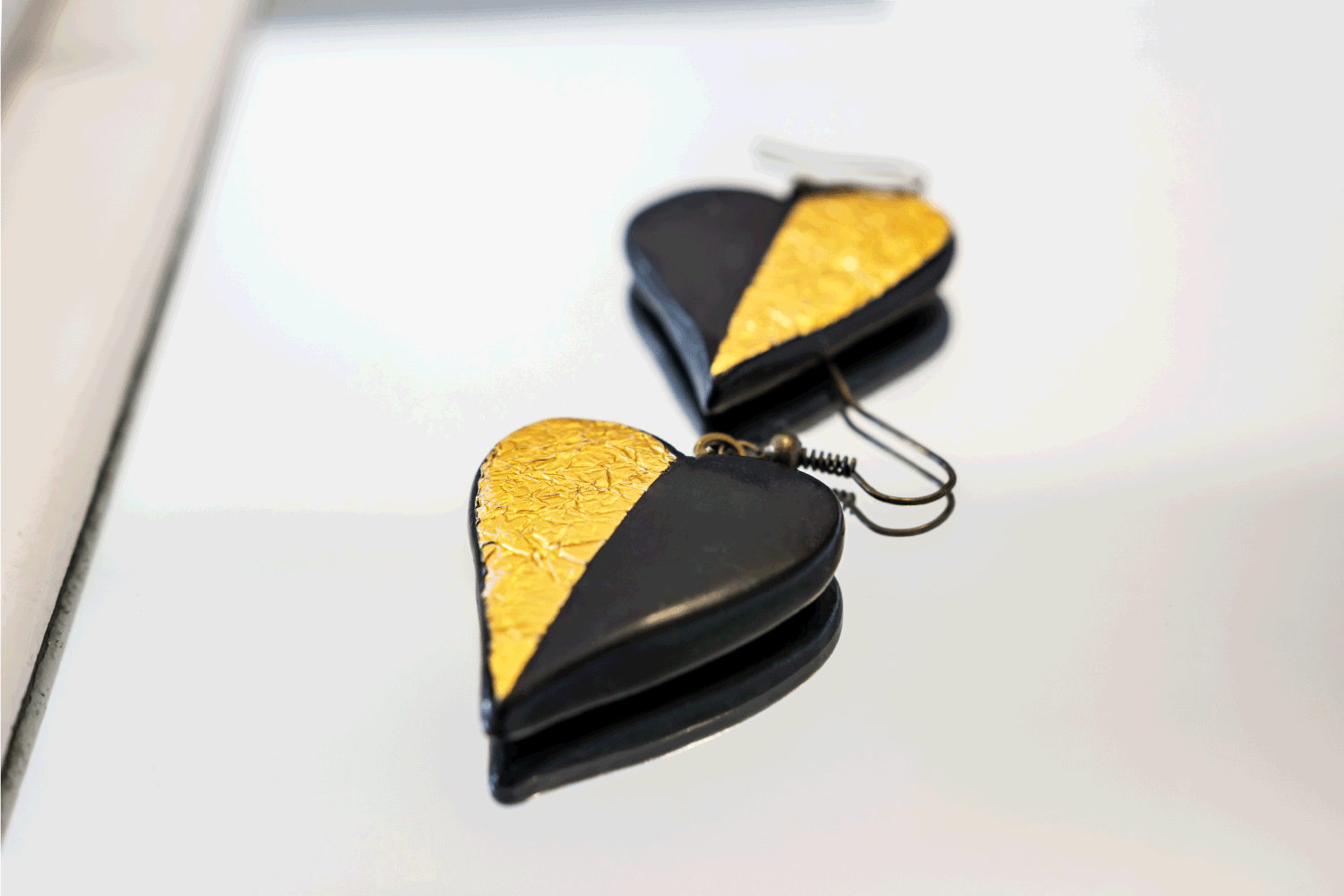 Close-up of handmade Fimo earrings inspired by love, delicate shapes and the everlasting combination of black and gold