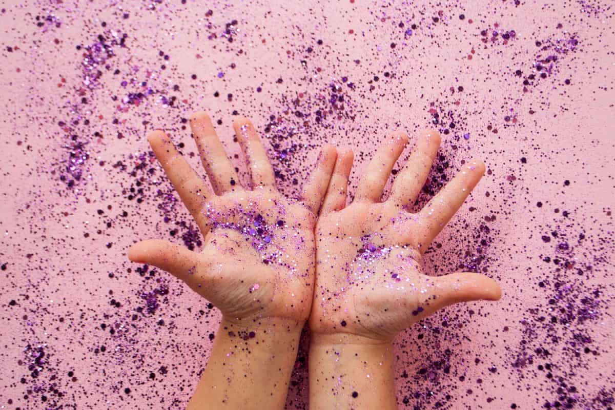 A child's hands holding purple colored glitter