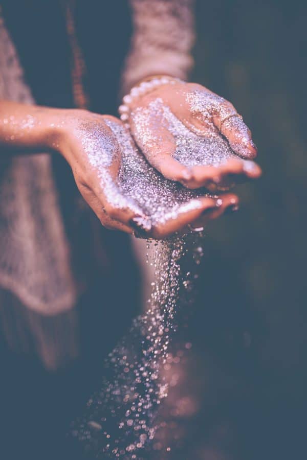 A woman holding silver colored glitter on her hands