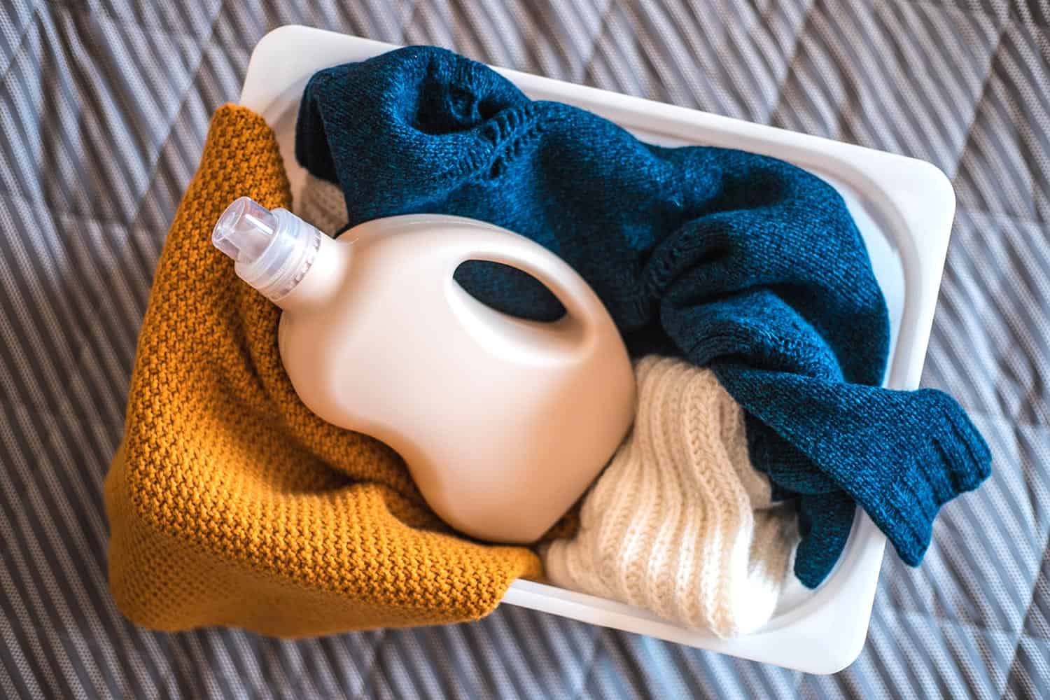 Bottle of detergent with sweaters in container