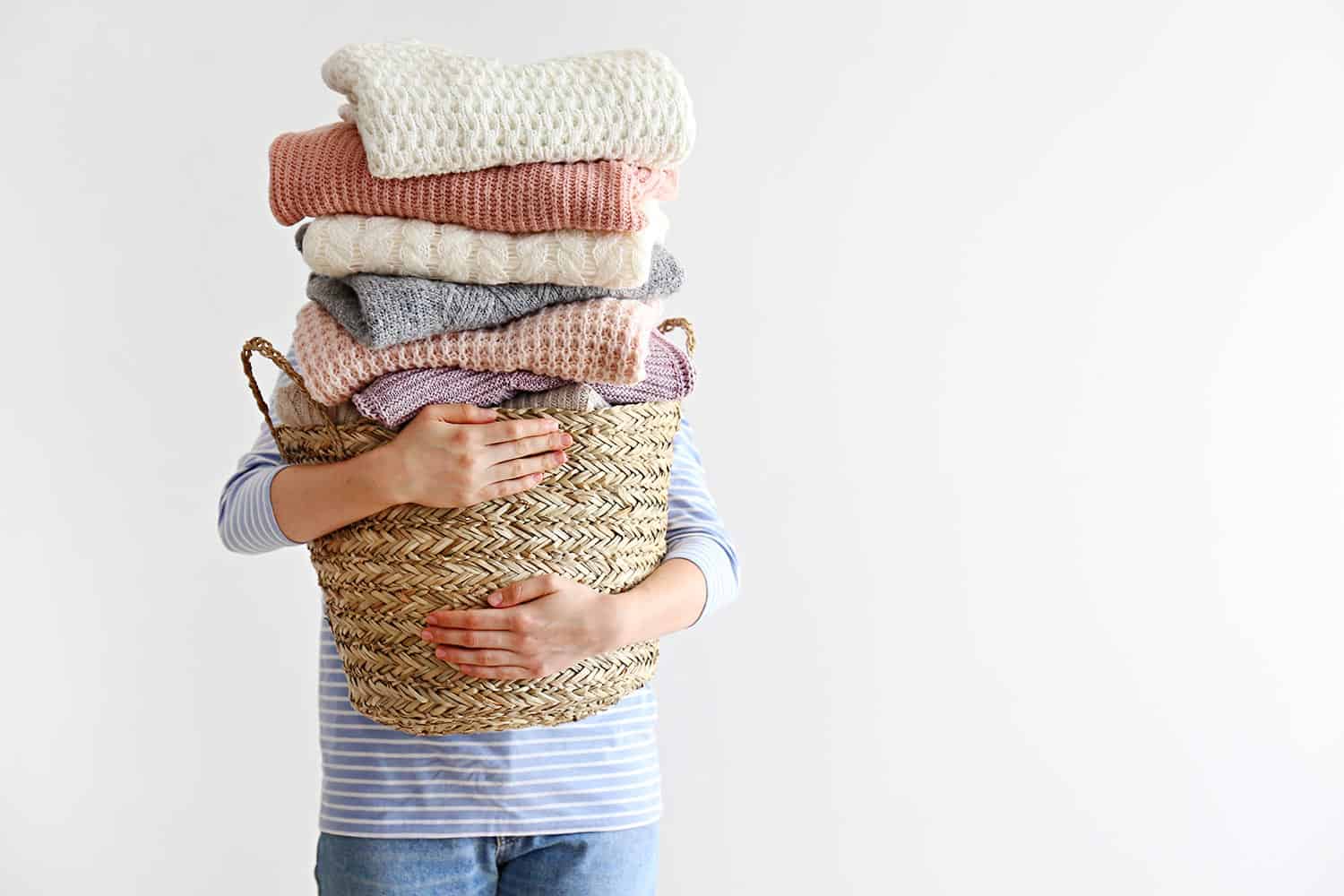 Pile of knitted sweaters of different colors and patterns perfectly stacked on woman's hands