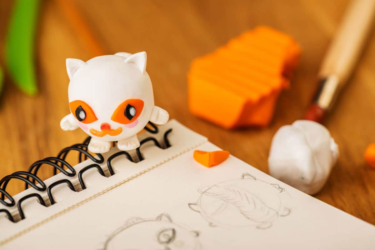 A white cat figurine made out of polymer clay placed on top of the notebook