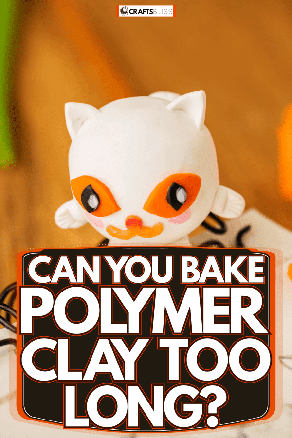 A white cat figurine made out of polymer clay placed on top of the notebook, Can You Bake Polymer Clay Too Long?