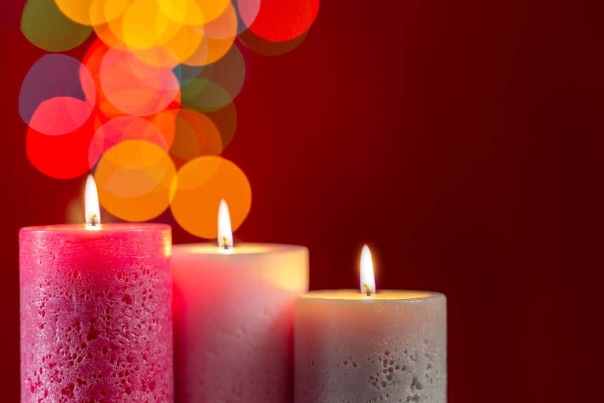 Three candles coated in glitter on a red background