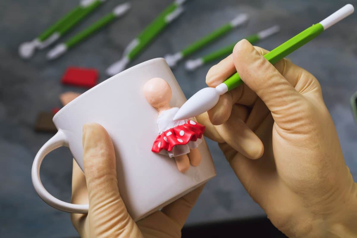 Woman painting the polymer clay figure on the side of the mug