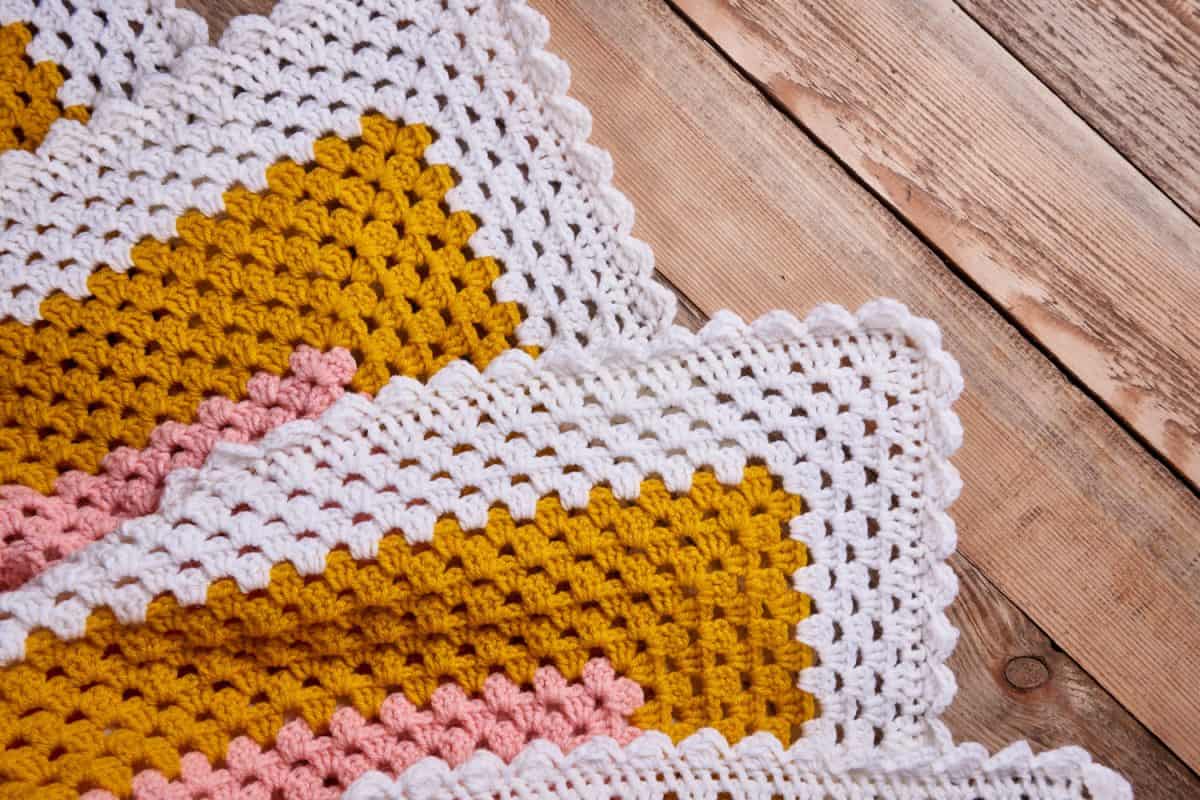 Needlework. Colorful woolen crocheted bedspread on a wooden background