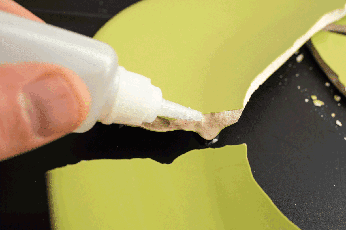 Hand applying liquid glue on ceramic broken pieces, repairing a green plate. Can You Glue Ceramic Back Together [And How To]