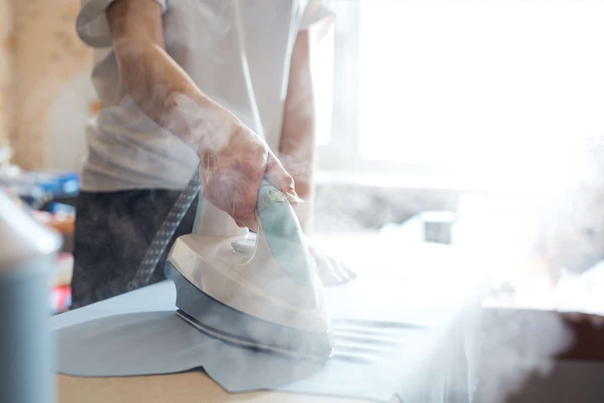 Woman tailor ironing textile with steaming on the iron board before starting work