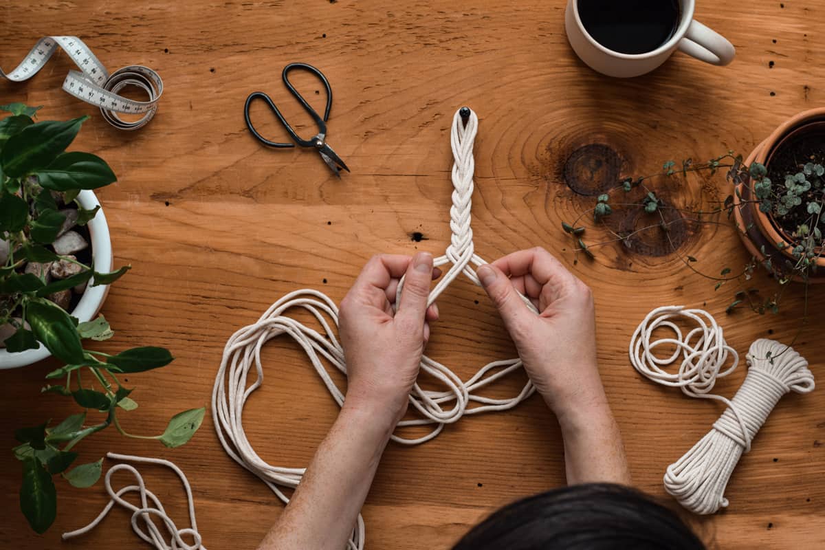 Top down view of woman making macrame rope plant hanger